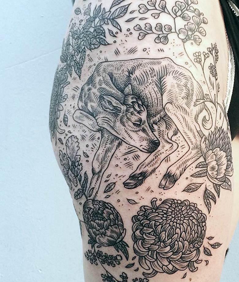 Braço tatuado com motivos animais e florais
