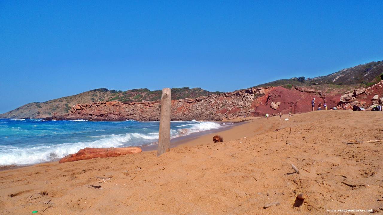 Na areia dourada avermelhada da praia Cala Pilar em Menorca